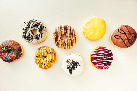 Various colorful creamy donuts with different glaze on top of them, isolated on white background.の写真素材