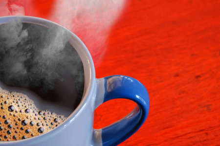Close up to hot coffee and smoke  in the cup on wooden desk.の写真素材