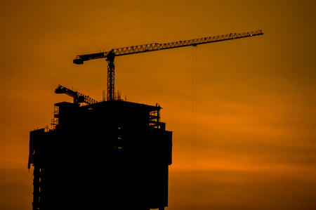 The industrial construction cranes and building silhouettesの写真素材