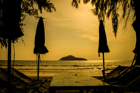 Tropical beach and umbrellas silhouettes in sunset lightの写真素材