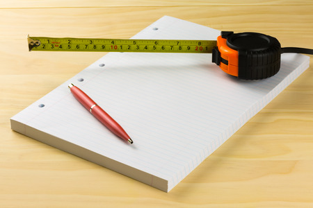 pen, tape measure and  paper on wood tableの写真素材