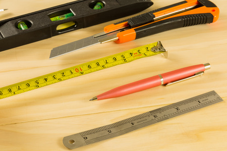 construction bubble spirit level tool, cutter, pen and ruler on wood table