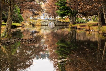 stone bridge and the trees reflected in Queenstown gardenの写真素材