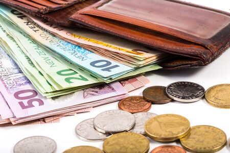 Dollar notes and coins in New Zealand currency in an old wallet isolated on white