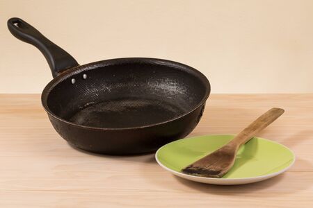 used non stick frying pan on wooden tableの写真素材