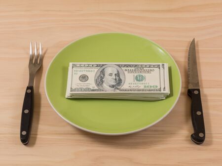 Dollar bills in plate on wooden tableの写真素材