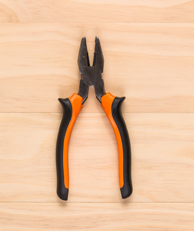 overhead shot image of pliers on wooden table