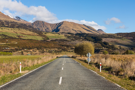 asphalt road through the field with mountain at the backgroundの写真素材