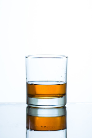 Glass of whiskey on glass table and white backgroundの写真素材