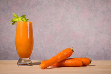 healthy fruit and vegetable smoothie with carrot on wooden tableの写真素材