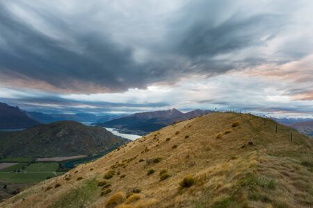 view of mountain, lake and dramatic clouds at sunset in Queenstown, New Zealandの写真素材