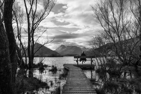 woman sits by Glenorchy lagoon in Glenorchy, New Zealandの写真素材