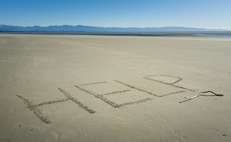 the word HELP written on sand on the beachの写真素材
