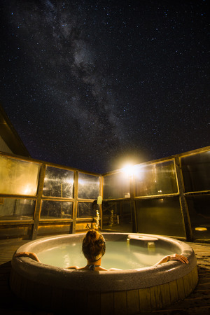 Back view of a young woman enjoying hot tub under the stars and milky way in New Zealandの写真素材