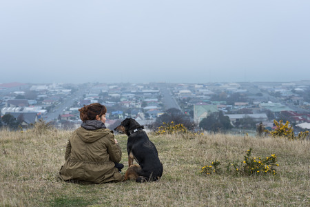 Young adult woman sitting with her dog on the hill in Oamaru, New Zealandの写真素材