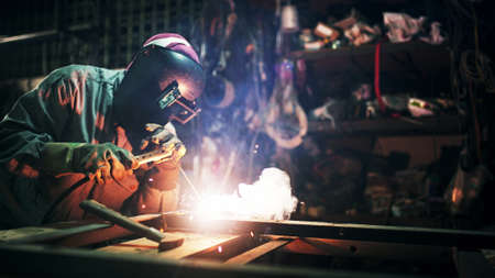 Working person About welder steel Using electric welding machine There are lines of light coming out and safety equipment in factory.の写真素材