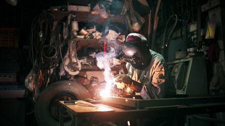 A craftman is welding with workpiece steel.working person about welder steel using electric welding machine there are lines of light coming out and safety equipment in factory industryの写真素材