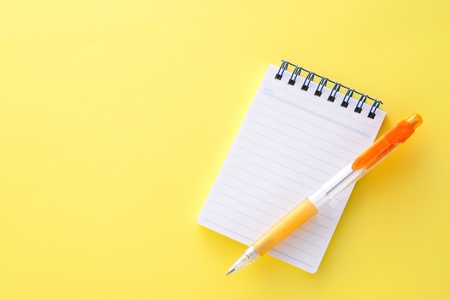 Notepad and pencil on yellow backgroundの写真素材