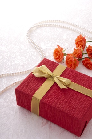 red gift box, red roses and pearl line on the white clothの写真素材