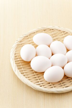many eggs in flat basket on wooden floorの写真素材