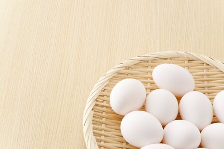 many eggs in flat basket on wooden floorの写真素材