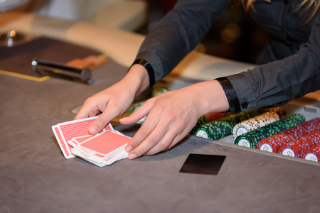 Closeup of hands of poker croupier with chips and cards in casinoの写真素材