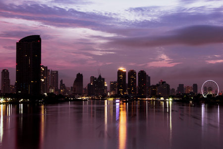 Purple sky at dawn by the Chaophraya river with the view of buildingsの写真素材