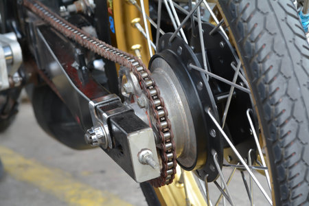 Detail of the rear wheel and chain of a vintage motorcycle.