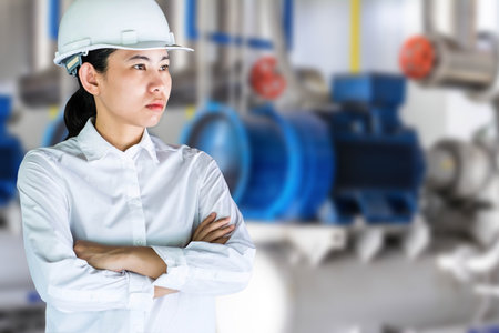 Portrait of serious female engineer standing with arms crossed at industrial plantの写真素材