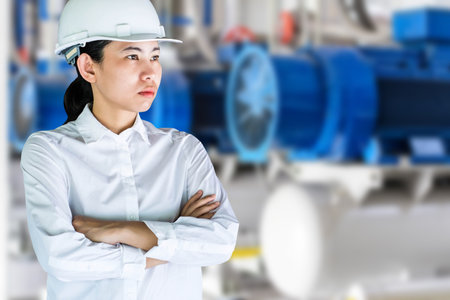Portrait of a female engineer standing with arms crossed against water treatment plantの写真素材