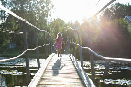 Happy Little Girl crossing suspension bridgeの写真素材
