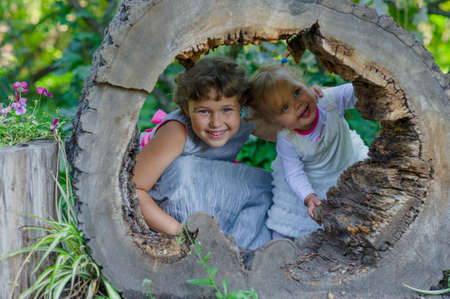Two funny little girls having fun with a sleigh in beautiful park.の写真素材