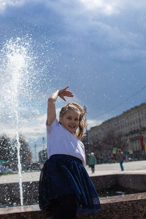 happy little cute girl having fun in splashes a fountainの写真素材