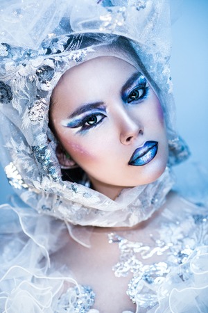 Winter beauty woman. Fashion portrait over blue snow Background.の写真素材