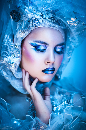 Winter beauty woman. Fashion portrait over blue snow Background.の写真素材
