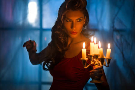 Beautiful woman in the dark room with a lot of candlesの写真素材