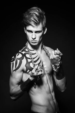 Muscular young man. Shot in a studio with chainの写真素材