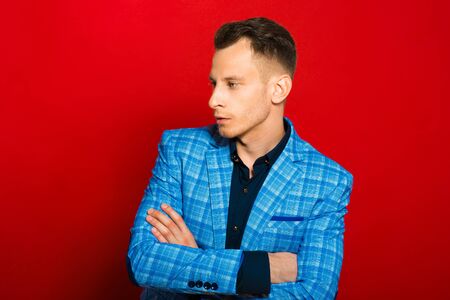 Portrait of young confident man dressed in tuxedo on red backgroundの写真素材