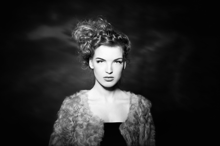 beautiful girl with curly hair in fur coat. Black and white photoの写真素材