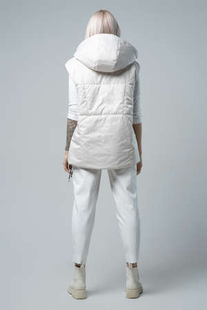 attractive woman in white vest and trousers looking at camera on grey backgroundの写真素材