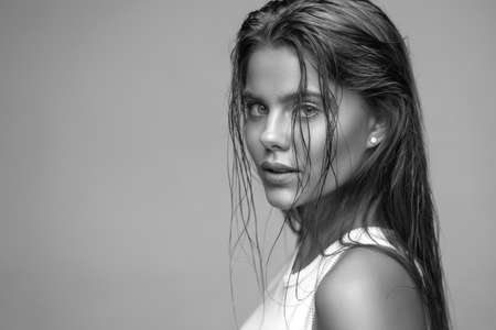 Beautiful young blue-eyed woman with wet skin and wet hairの写真素材