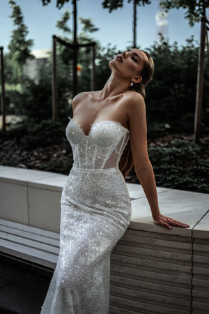 stylish fit bride in white wedding dress is standing fashion with hand on waist and looking straight with smile on the gray street building background at city. wedding lifestyle concept, free spaceの写真素材