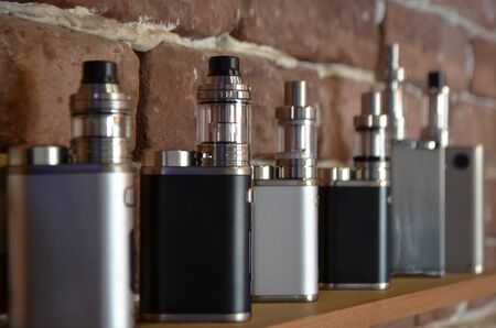 Electronic cigarette on a background of vape shop. E-cigarette for vaping. Popular vape devicesの写真素材