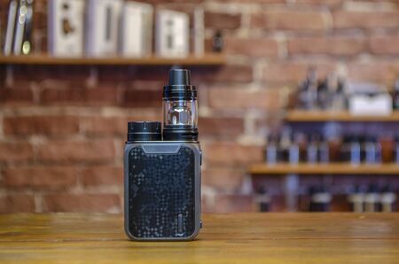 Electronic cigarette on a background of vape shop. E-cigarette for vaping. Popular vape devices