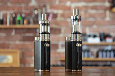 Electronic cigarette on a background of vape shop. E-cigarette for vaping. Popular vape devices
