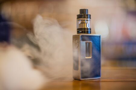 Electronic cigarette on a background of vape shop. E-cigarette for vaping. Popular vape devices