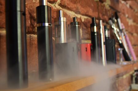 Electronic cigarette on a background of vape shop. E-cigarette for vaping. Popular vape devicesの写真素材