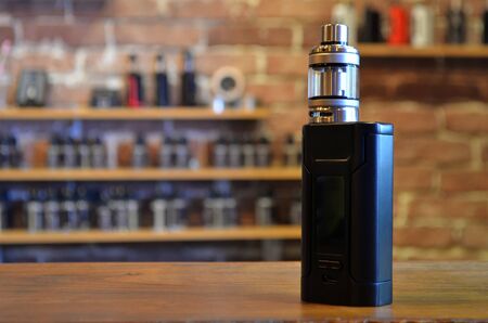 Electronic cigarette on a background of vape shop. E-cigarette for vaping. Popular vape devices