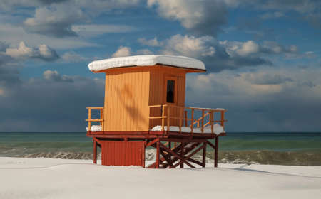 An orange lifeguard tower on a snowy beach in winterの写真素材