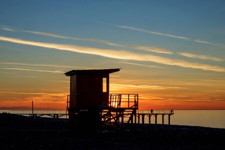 lifeguard tower silhouette on the blue and orange sunset beachの写真素材